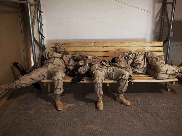 NATO troops from Georgia sleep on a bench while waiting for a flight at Camp Bastion in southern Afghanistan