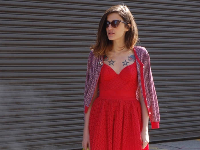 Guest of a Guest spotted this stylish woman, with her sweet red dress and cardigan and edgy tattoos, on the streets during New York fashion week.