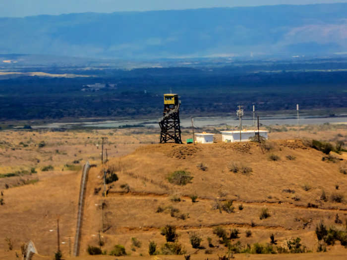 Guard towers dot the hilltops along the perimeter fence.