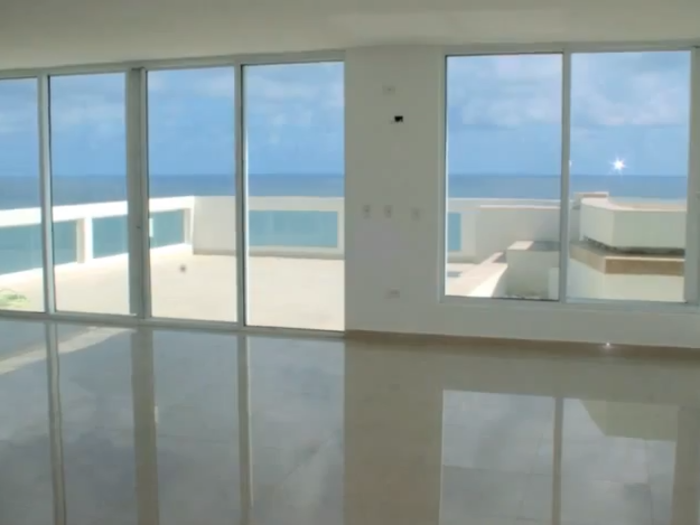 The penthouse features floor-to-ceiling windows offering incredible views of the seaside