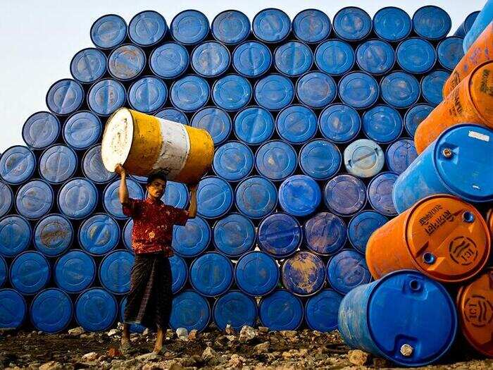 A Bangladeshi day worker piles 33-pound chemical drums in Dhaka.