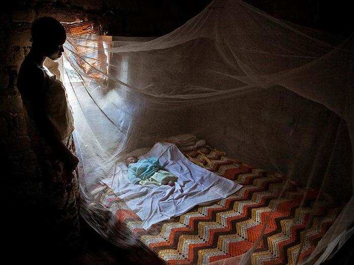 Twenty-year-old Christine watches her baby through a mosquito net in the Republic of Congo.