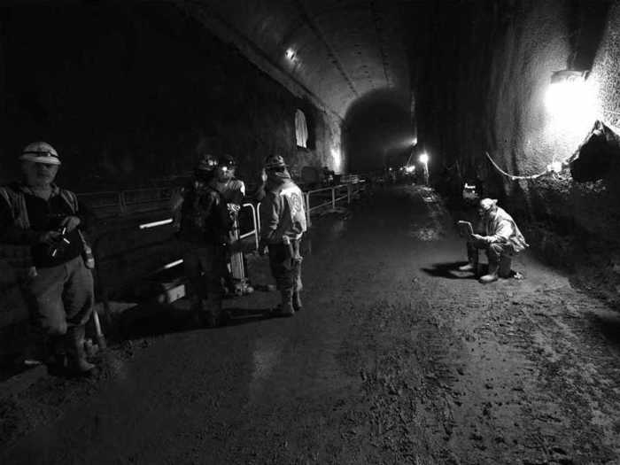 One construction worker takes a break to read the newspaper under a massive light.