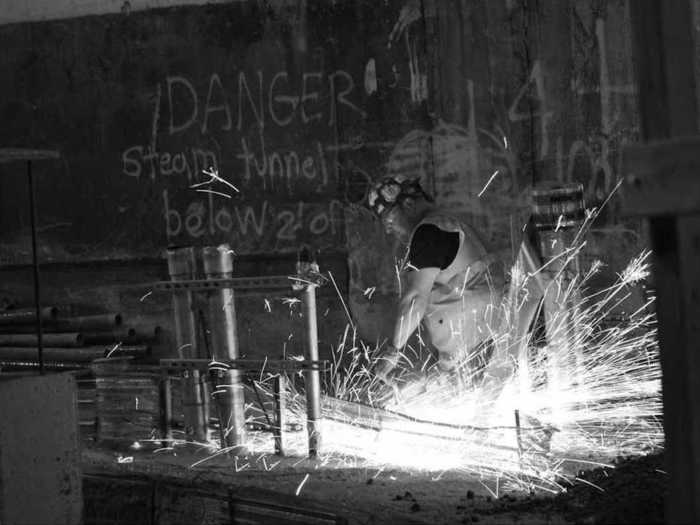 A man welds underneath a DANGER sign.