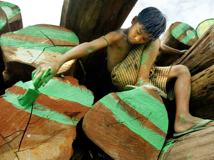 A young Burmese boy labels teak logs marked for export.