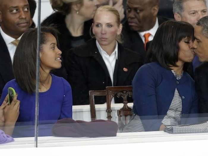 Sasha Obama snaps a picture of her parents stealing a kiss in the reviewing stand.