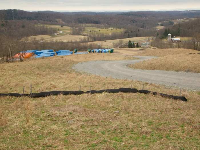 Looking down from the well site, you can see the containers that were used to store water to be mixed with frac fluid while the site was being drilled (they