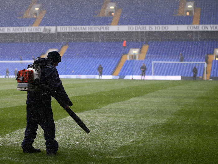 A worker clears snow before the game with a leaf blower