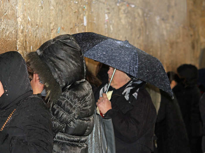 Despite the rain and late hour, pilgrims gather to pray at the Wall, one of the most sacred sites of the Jewish faith.