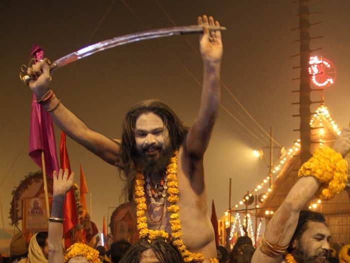 Naked Hindu holy men wearing marigold garlands bathe in the river.