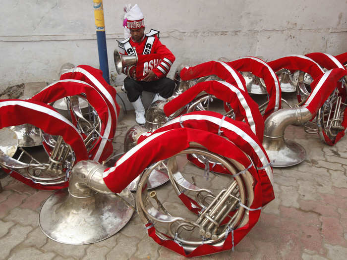 A member of an Indian brass band checks his instrument ahead of the procession.