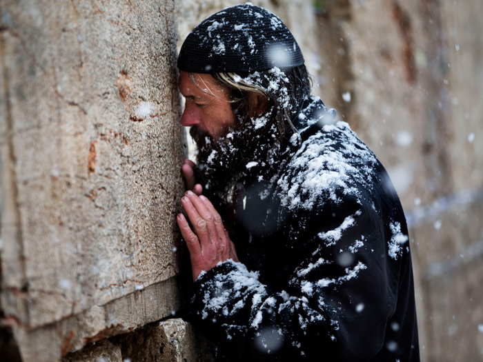 An orthodox Jewish man prays in the snow