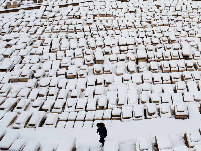 A man walks through tombs covered by snow on the Mount of Olives