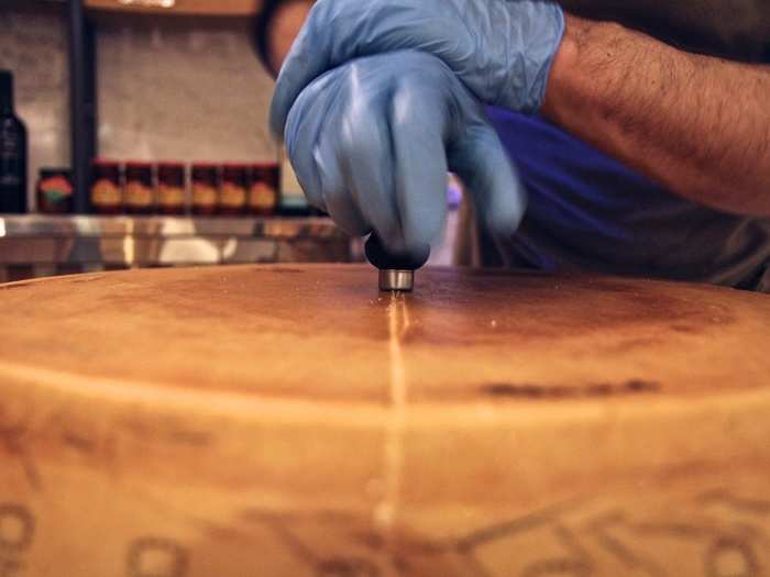 Cheese monger Craig Ulmer carefully cuts a wheel.