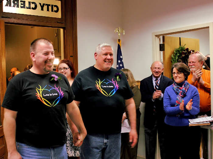 Two men emerge from their ceremony to applause from everyone waiting outside the clerk