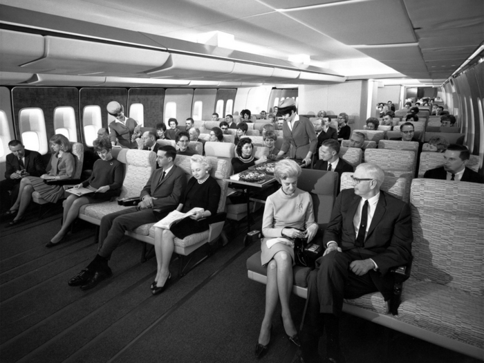 Passengers aboard a Boeing 747 enjoy the spacious economy class configuration (date unknown).