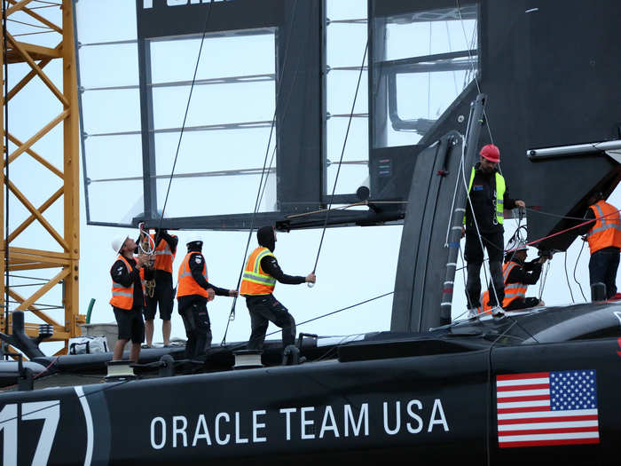 The crew wait for the wing to make it over the hull before grabbing ropes to guide it into place.