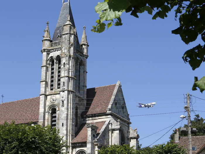 Here, a commercial airliner flies over the 14th century Eglise St. Pierre et St. Paul Church (it