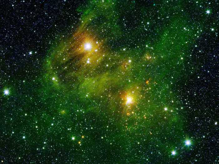 Two extremely bright stars omit a greenish fog, comprised of carbon and hydrogen compounds found right here on Earth in vehicle exhaust.