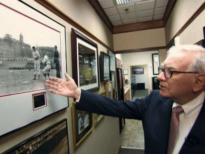 Down a hallway of sports-related photos. Buffett is pointing to a picture of former Red Sox player Ted Williams. He takes a lot of tips from Williams