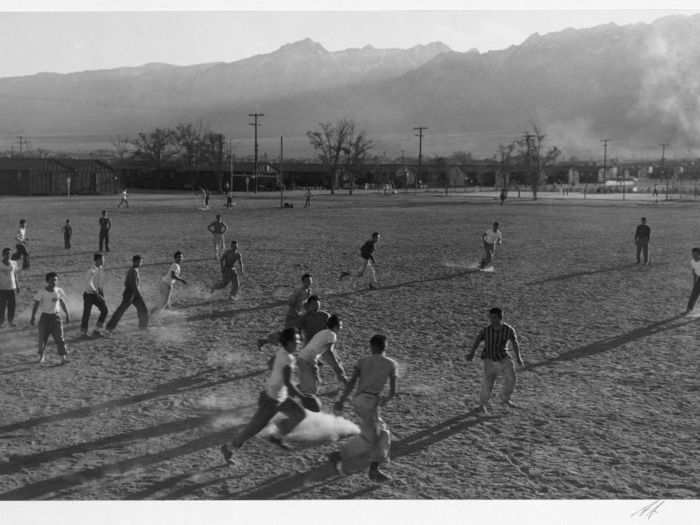 Men play American football on a dusty field.