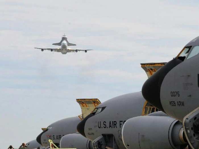 An aircraft carrying the Space Shuttle Discovery performs a flyby over Joint Base Andrews.