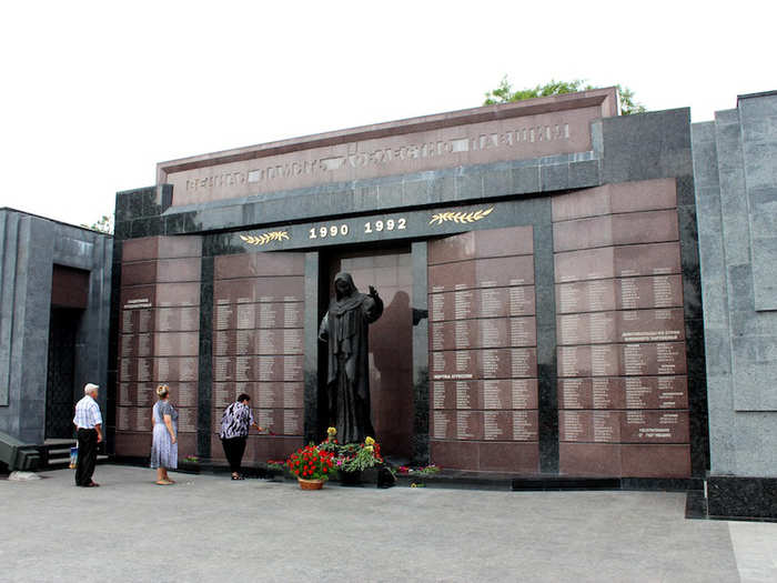 Transnistrians queue to leave flowers beside a war memorial.