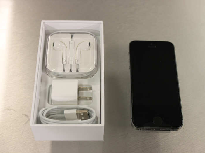 The headphones and charging cable are stored underneath the iPhone 5S.