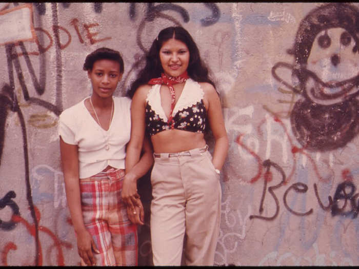 Two Latino girls pose in front of graffiti in Lynch Park, Brooklyn.