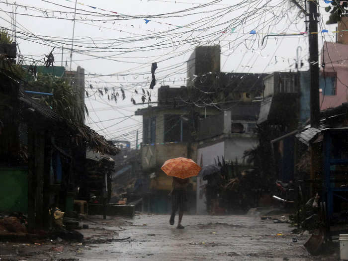 A man tries to cover himself with an umbrella during heavy rain brought by Cyclone Phailin.