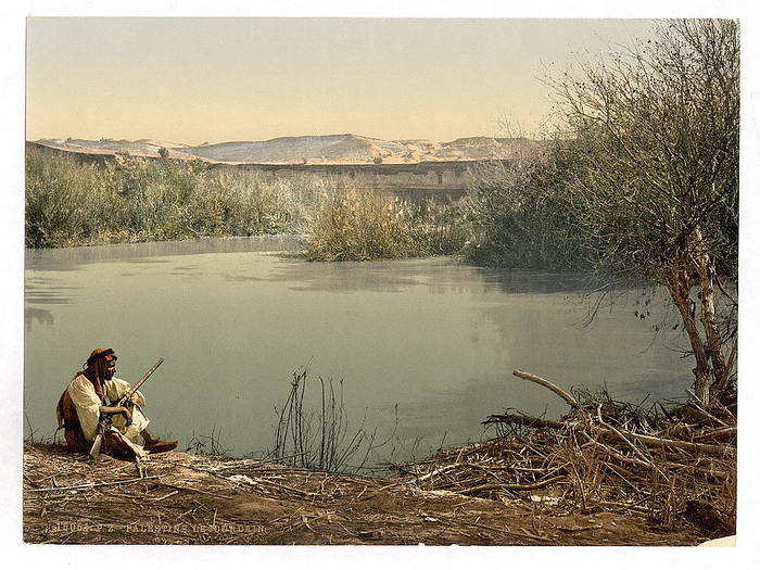 A man sits by the River Jordan