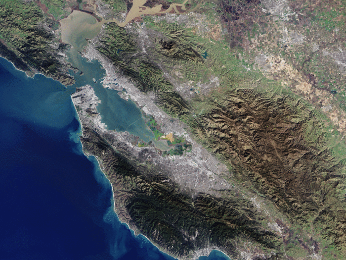 In this photo of the San Francisco Bay Area, you can see San Francisco on the peninsula in the center-left. The Golden Gate Bridge is just barely visible connecting the opening of the bay. The straight diagonal line running down the peninsula is the San Andreas Fault, responsible for the numerous earthquakes in the area.