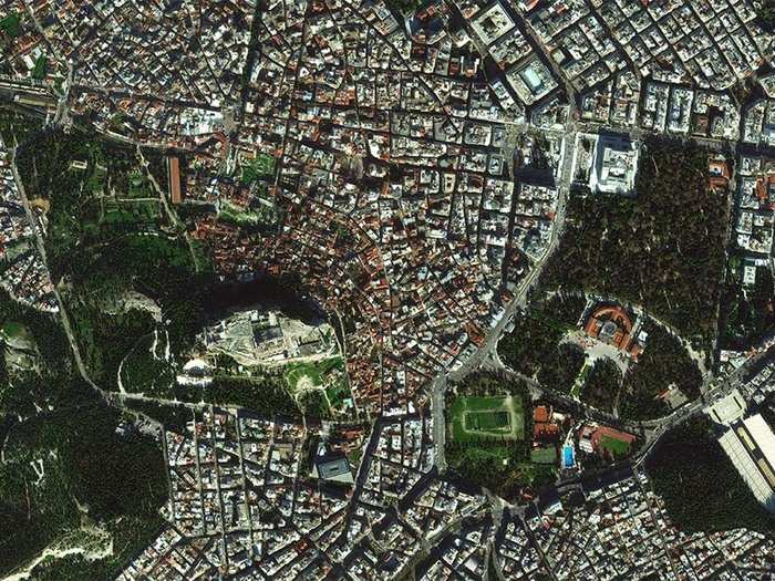 This photo of central Athens, Greece was taken this past January. In the center is the Acropolis of Athens. You can tell it is super tall — it casts a shadow it on the city to the north. In the lower right, you can see the large, white marble Panathenaic Stadium.