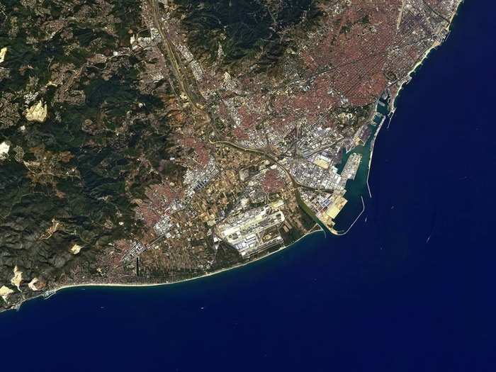 The Spanish city of Barcelona is pictured here. On the left, are the Garraf Massif Mountains. The large yellow patches are degraded land from rock quarries and garbage dumps. This was taken by Japan