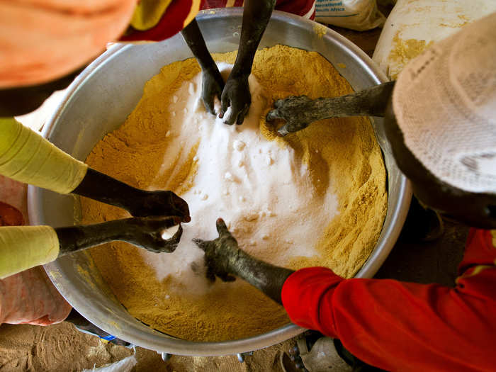 Volunteers of Kuwait Patients Helping Fund prepare a mixture for feeding malnourished children in the Abu Shouk refugee camp in North Darfur.