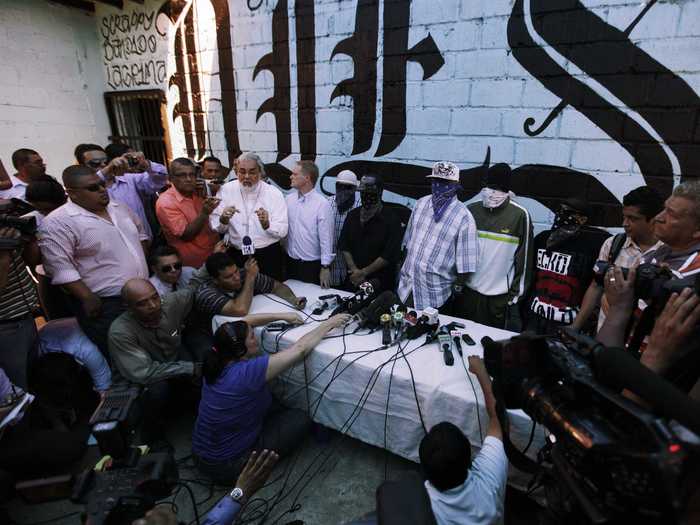 As a last resort, the church brokered a truce in May 2013 between gangs "Calle 18" and "Mara Salvatrucha." Below, masked members speak to the press with San Pedro Sula