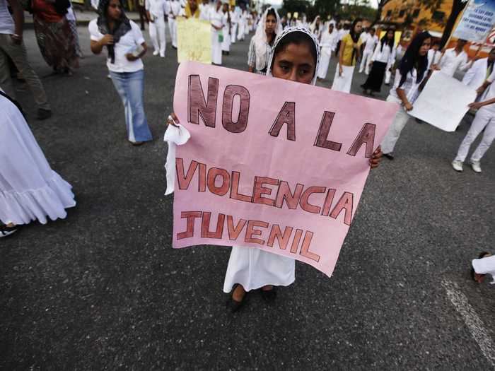 Whatever the future holds for Honduras, citizens continue to plead for action. Here, a devotee of the Light of the World Church holds a protest sign reading: "No to juvenile violence."