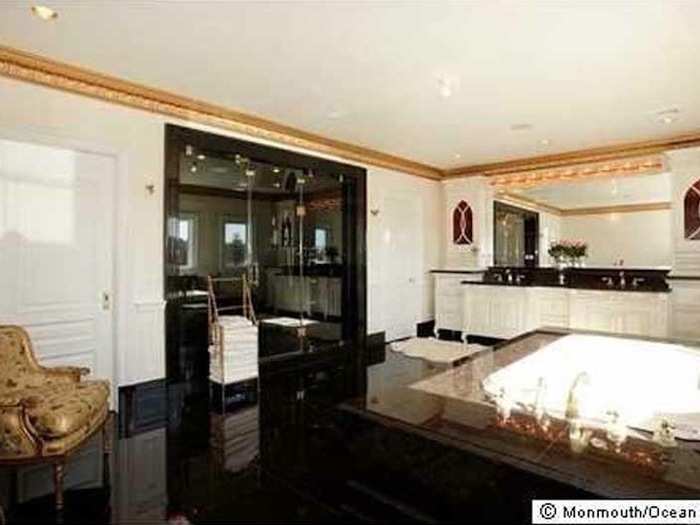 The master bathroom has black marble and a tub.