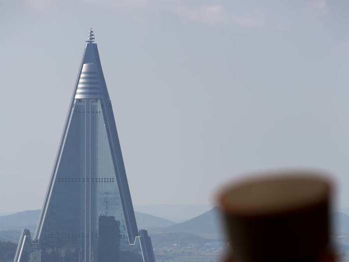 A soldier stands in front of the Ryugyong Hotel. It has been in construction since 1987 and has yet to open. Egypt-based Orascom has agreed to help finish the tower in exchange for rights to providing mobile phone service in North Korea.