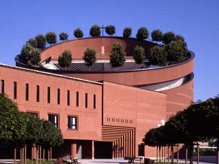 Cathe´drale de la Re´surrection, a Roman Catholic cathedral in Évry, France, is unique for its rotund main sanctuary. Designed by Mario Botta Architetto, it is finished with brick and topped with 24 linden trees, meant to symbolize life.