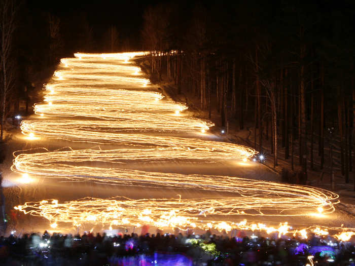 Skiers go down the slopes holding lit torches in Russia.