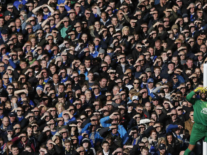 English Premier League fans and Everton goalie Tim Howard shield their eyes from the sun.