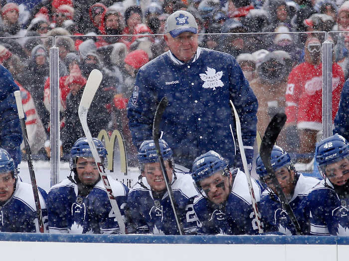 Maple Leafs head coach Randy Carlyle went with a simple baseball cap as snow fell from above.