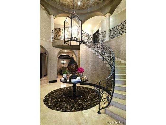 Inside, a staircase with wrought-iron railings leads from the foyer to the second floor.