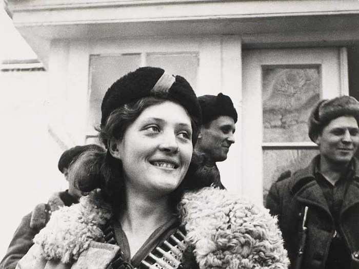 In 1942, a Russian female partisan stands covered in ammunition.