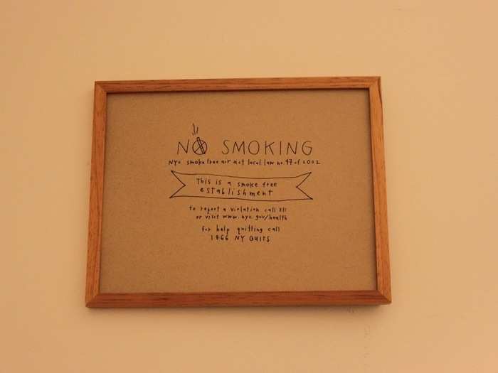 Small, simple signs with faux handwritten font prohibit smoking in the cafe (and offer a number if you