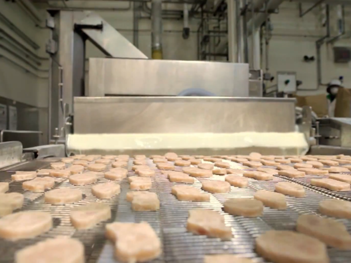 Then the nuggets travel down the assembly line to be covered in a light batter, which is shown in the center of this photo.