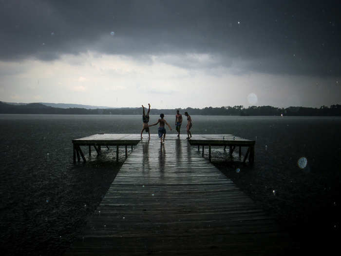 Four friends celebrate on a dock, during a surprise rain shower.