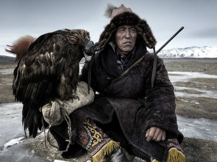 A hunter in Western Mongolia rests with his eagle.