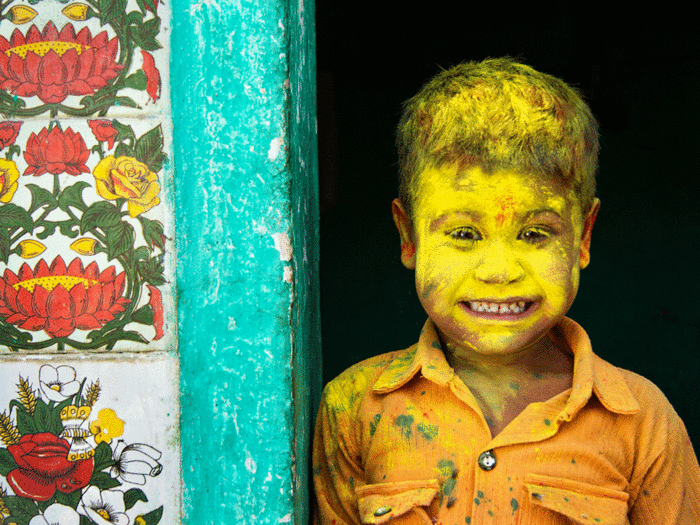 A young Indian boy is covered in colorful Holi powder during the Spring Holi festival.